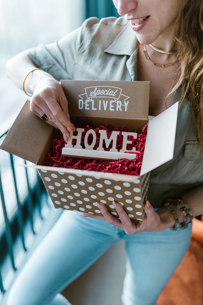 who-we-are A woman opening a polka dot box labeled 'Special Delivery' with 'HOME' inside.